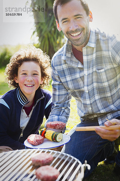 Portrait lächelnder Vater und Sohn beim Grillen