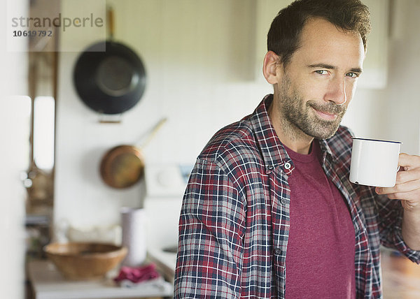 Portrait lächelnder brünetter Mann beim Kaffeetrinken in der Küche