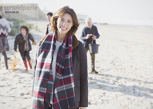 Portrait lächelnde Frau im karierten Schal mit Familie am Strand