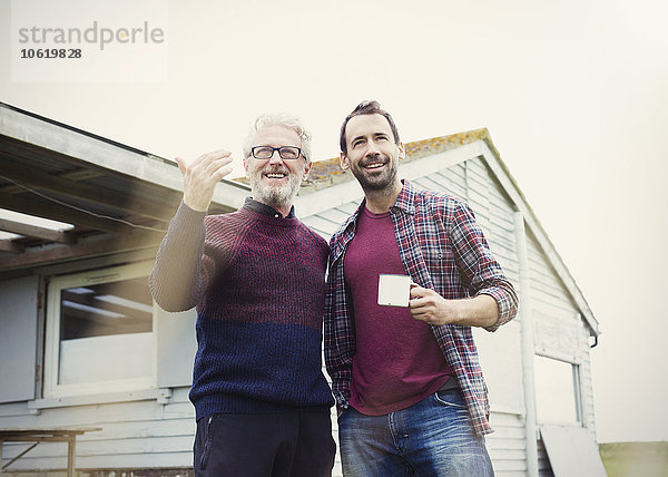 Vater und Sohn reden und trinken Kaffee vor dem Haus.