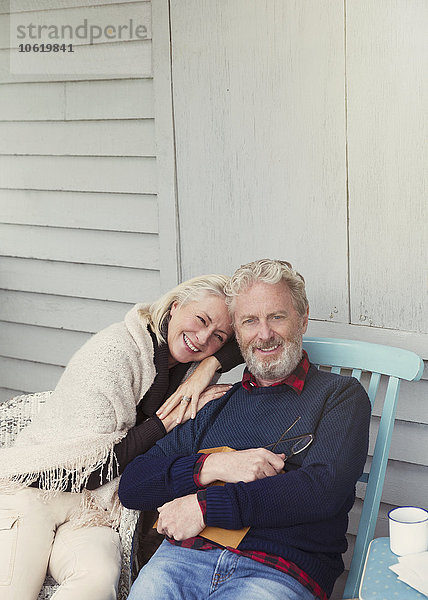 Portrait lächelndes Seniorenpaar  das sich auf der Terrasse umarmt