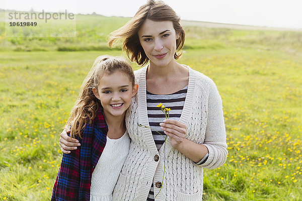 Portrait lächelnde Mutter und Tochter auf Wiese mit Wildblumen