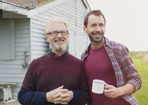 Portrait lächelnder Vater und Sohn beim Kaffeetrinken im Freien