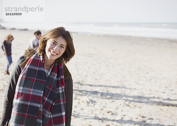 Portrait lächelnde Frau im karierten Schal am sonnigen Strand