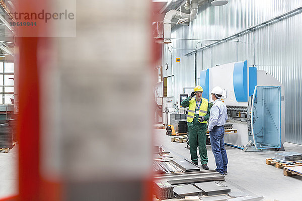 Ingenieur und Arbeiter im Gespräch in der Fabrik