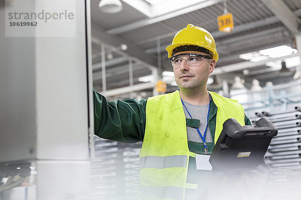 Arbeiter in Arbeitsschutzkleidung am Schaltschrank im Werk