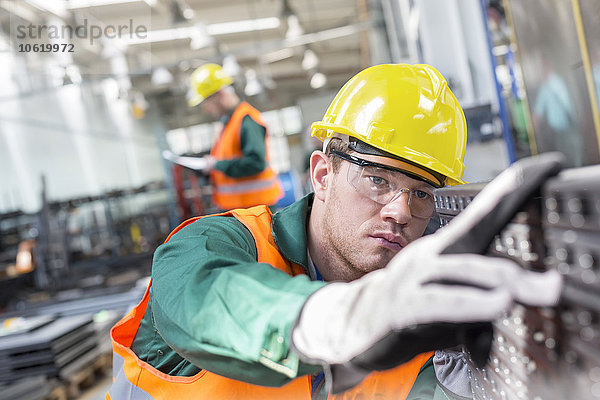 Fokussierter Arbeiter beim Prüfen von Stahlteilen in der Fabrik