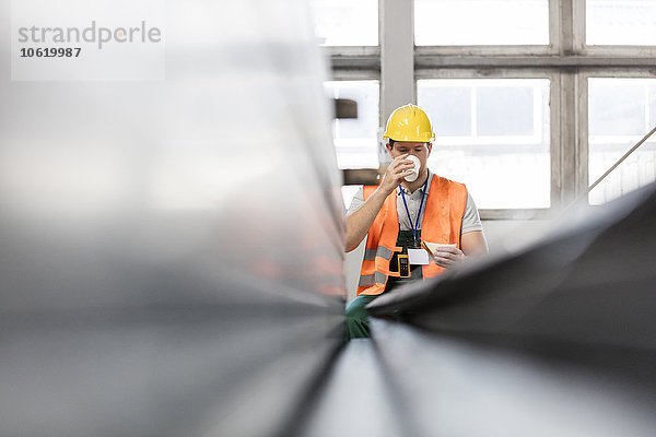 Arbeiter in Arbeitsschutzkleidung beim Kaffeetrinken in der Fabrik