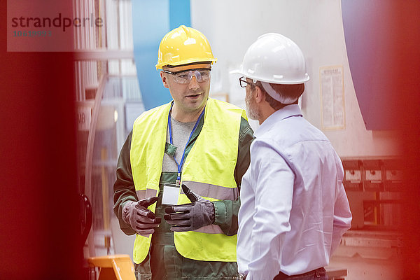 Ingenieur und Arbeiter im Gespräch in der Fabrik