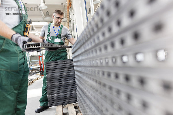 Arbeiter beim Heben von Stahlteilen im Werk