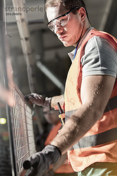 Fokussierter Arbeiter hält Stahlteil in der Fabrik