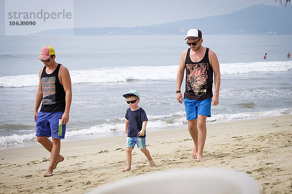 Mexiko  Nayarit  zwei junge Männer und ein kleiner Junge  die am Strand spazieren gehen.
