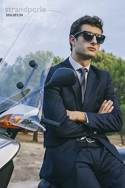 Porträt eines jungen Geschäftsmannes mit Sonnenbrille auf dem Motorroller