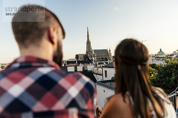 Österreich  Wien  Rückansicht des jungen Paares auf der Dachterrasse mit Blick auf den Stephansdom
