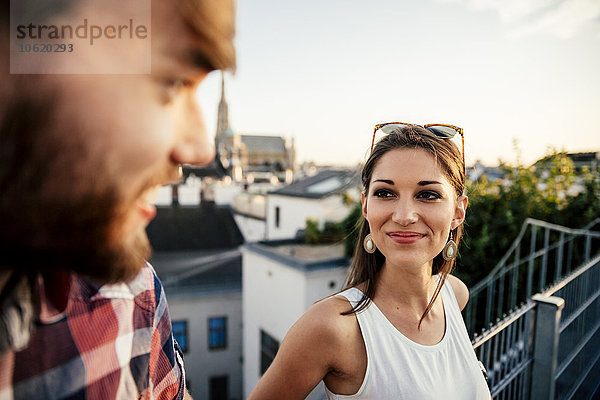 Österreich  Wien  Porträt einer lächelnden jungen Frau von Angesicht zu Angesicht mit ihrem Freund auf einer Dachterrasse