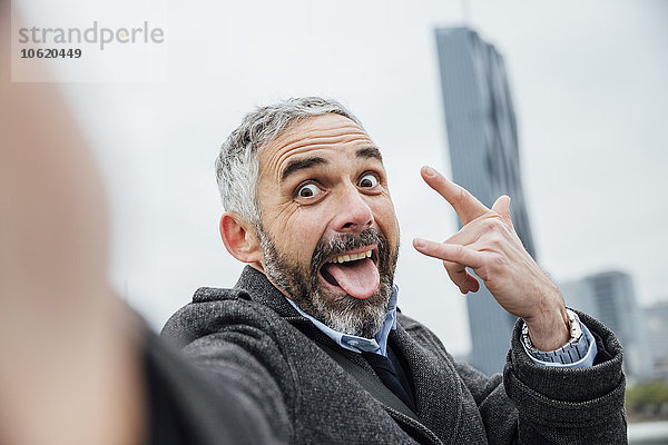 Österreich  Wien  Porträt eines Geschäftsmannes mit schmollendem Mund  der mit seinem Smartphone einen Selfie nimmt.