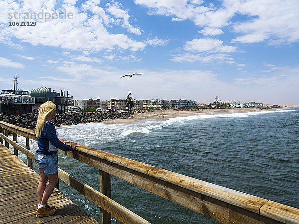 Namibia  Swakopmund  blonde Frau mit Blick von Pier zu Strand