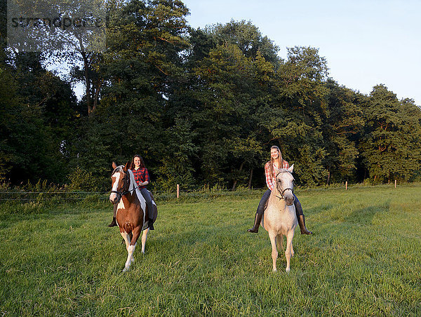 Zwei junge Frauen auf ihren Pferden