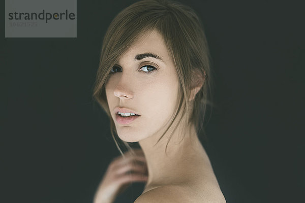 Porträt einer attraktiven nackten jungen Frau vor schwarzem Hintergrund