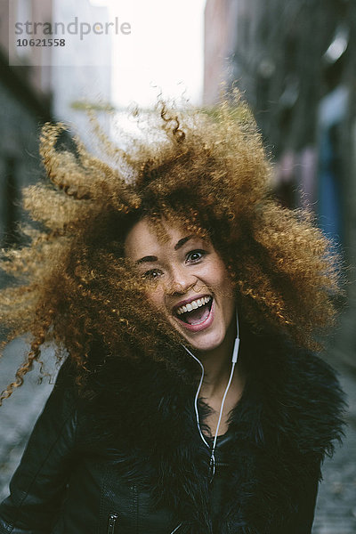 Porträt einer glücklichen Frau mit Afro-Hörmusik mit Kopfhörern
