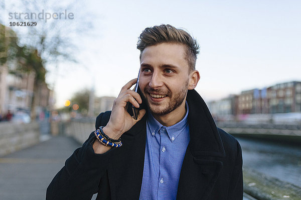 Irland  Dublin  Portrait eines jungen Geschäftsmannes beim Telefonieren mit Smartphone