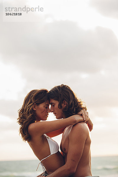 Romantisches  junges Paar  das sich am Strand umarmt.