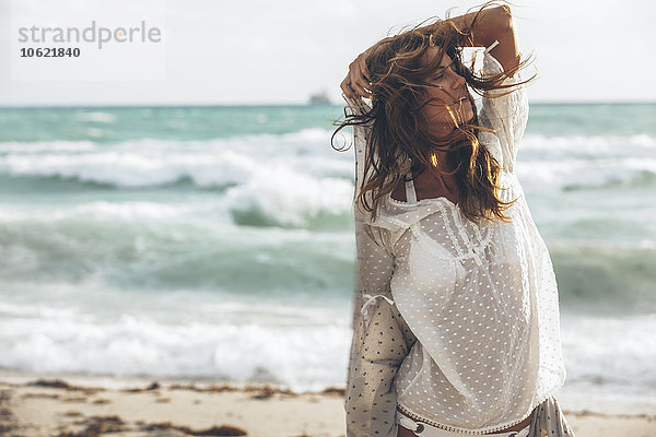 Hübsche junge Frau in Strandkleidung am Strand