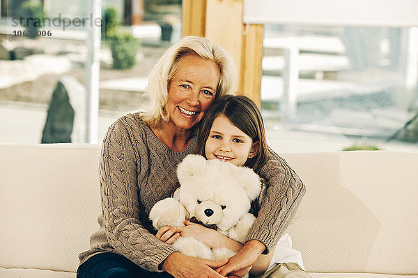 Porträt der lächelnden Großmutter mit Enkelin  die den Teddybären hält
