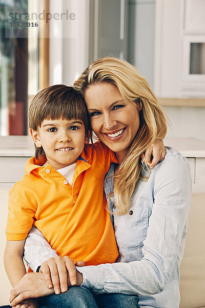 Porträt der lächelnden Mutter mit Sohn auf dem Schoß