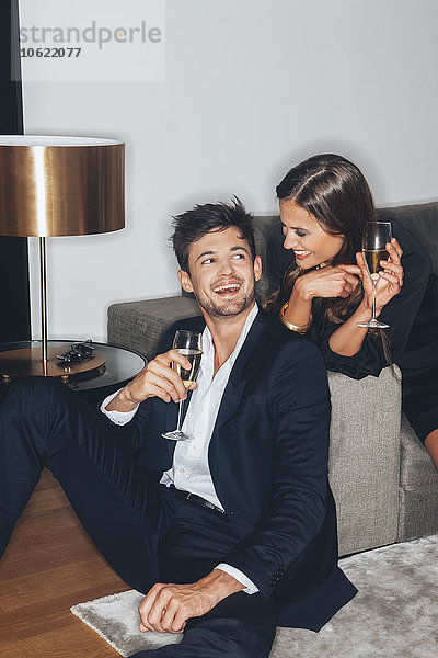 Glückliches junges Paar mit Gläsern Champagner auf dem Sofa