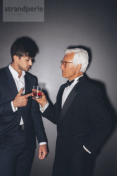 Junger Mann im Gespräch mit einem eleganten älteren Mann mit einem Drink