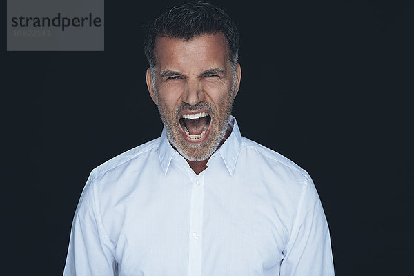 Porträt des schreienden Mannes weißes Hemd vor schwarzem Hintergrund