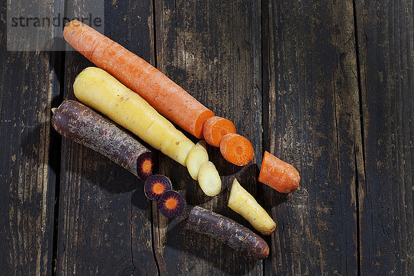 Drei verschiedene Arten von geschnittenen Karotten auf dunklem Holz