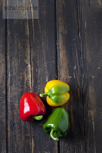 Rote  gelbe und grüne Paprika auf dunklem Holz