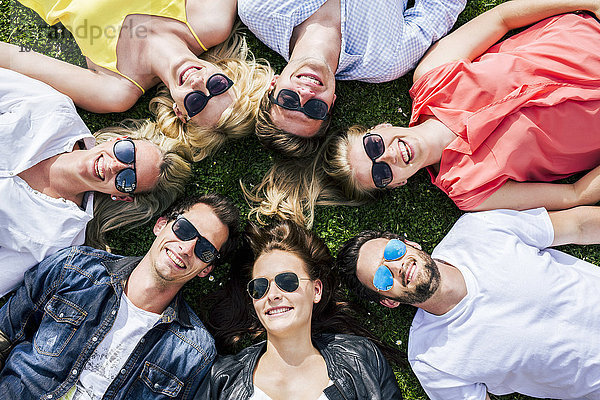 Glückliche Freunde mit Sonnenbrille auf der Wiese liegend