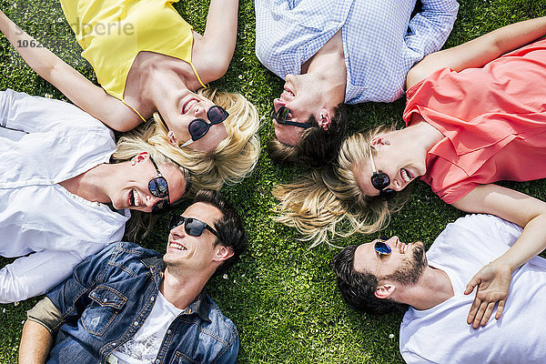 Glückliche Freunde mit Sonnenbrille auf der Wiese liegend