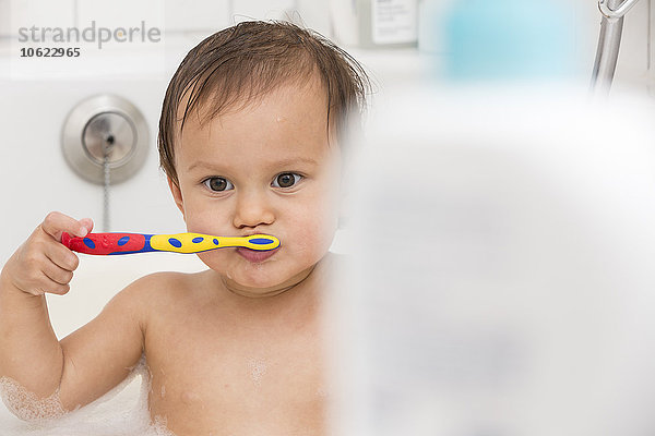 Portrait eines Mädchens beim Zähneputzen in einer Badewanne