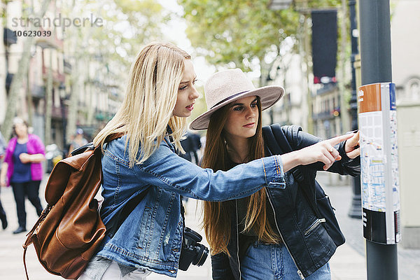 Spanien  Barcelona  zwei junge Frauen beim Blick auf den Stadtplan am Pol