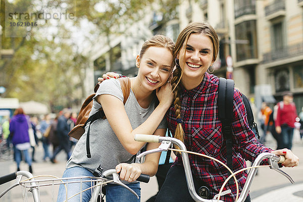 Spanien  Barcelona  zwei junge Frauen auf Fahrrädern in der Stadt
