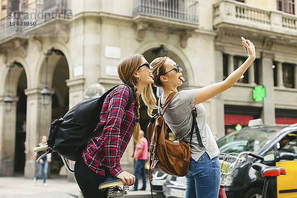 Spanien  Barcelona  zwei verspielte junge Frauen  die einen Selfie nehmen.