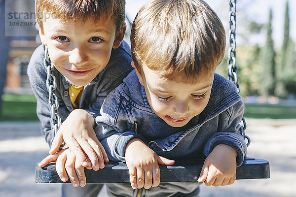 Zwei glückliche Jungs auf einer Schaukel auf dem Spielplatz