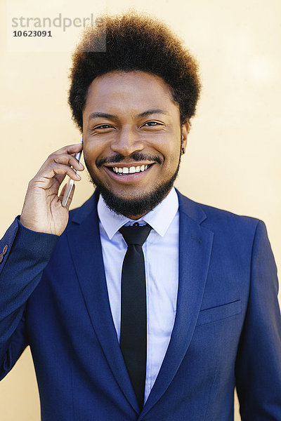 Porträt eines lächelnden jungen Geschäftsmannes beim Telefonieren mit dem Smartphone