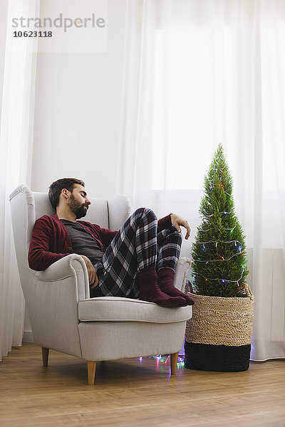 Mann schlafend auf Sessel zu Hause zur Weihnachtszeit