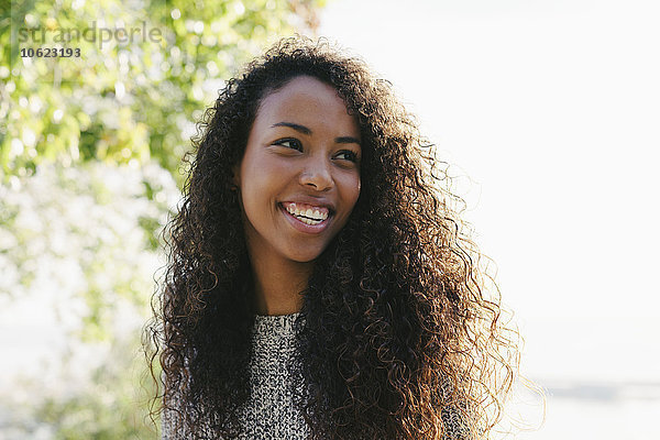 Spanien  Barcelona  Porträt einer lächelnden jungen Frau mit lockigem braunem Haar