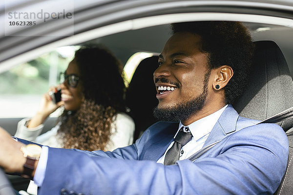 Porträt eines lächelnden Geschäftsmannes im Auto mit seinem Kollegen