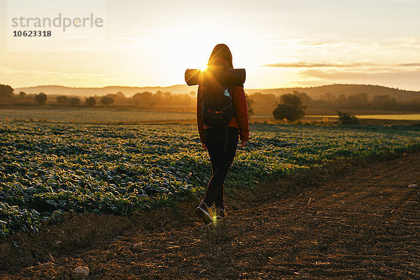 Spanien  Katalonien  Girona  Frau  die bei Sonnenaufgang auf dem Feldweg wandert