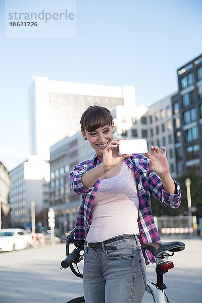Deutschland  Berlin  junge Frau beim Fotografieren mit ihrem Smartphone