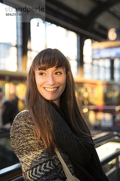 Deutschland  Berlin  lächelnde junge Frau wartet am Bahnsteig