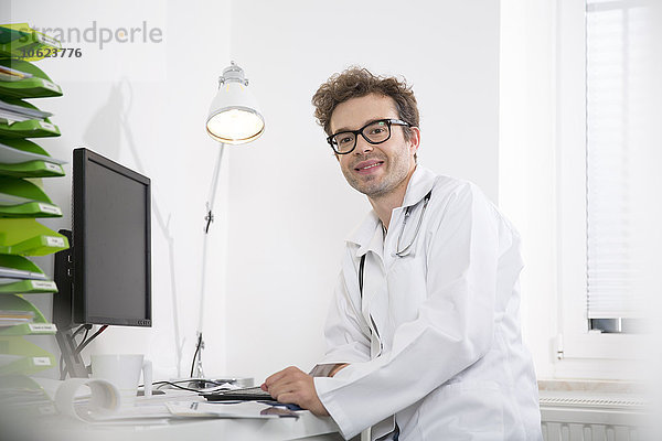 Porträt eines lächelnden Arztes am Schreibtisch