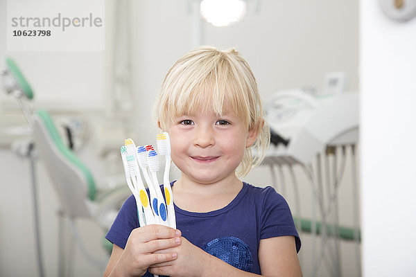 Mädchen in der Zahnarztpraxis mit Zahnbürsten